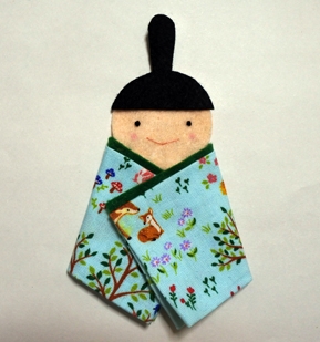 ⑧左から、ふくの端を斜めに折り、着物のようにし（このときかおとふくの境目を隠すようにする）、ボンドで止める。